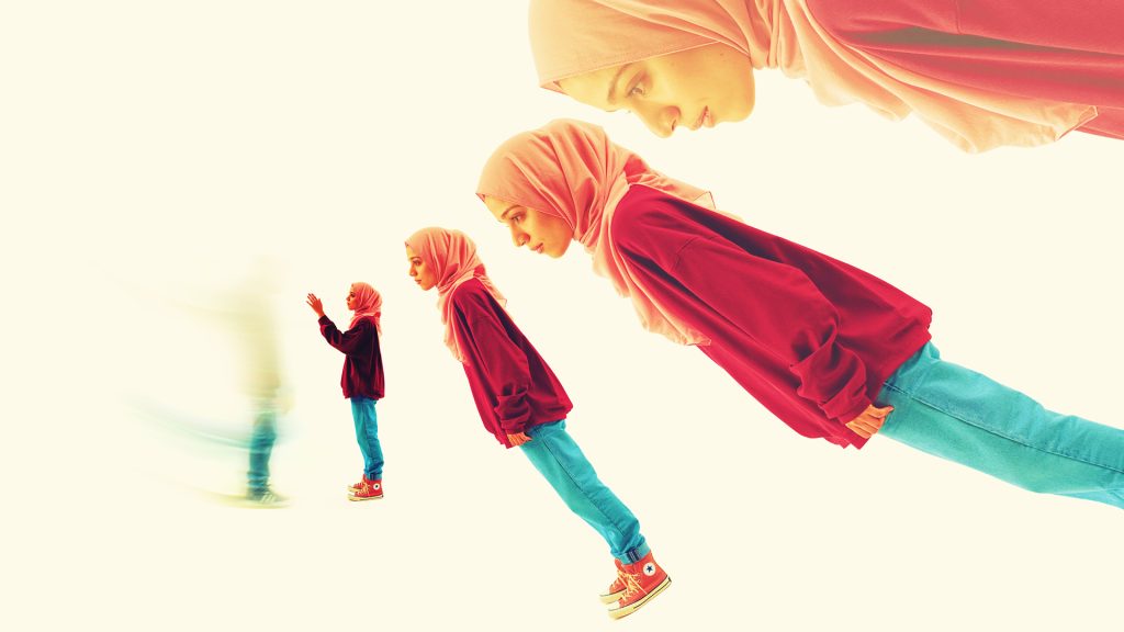 A photo of a young girl on a plain cream coloured background in blue jeans, red hoodie and pink hijab. Her image is repeated several times in a semicircular pattern, at different sizes