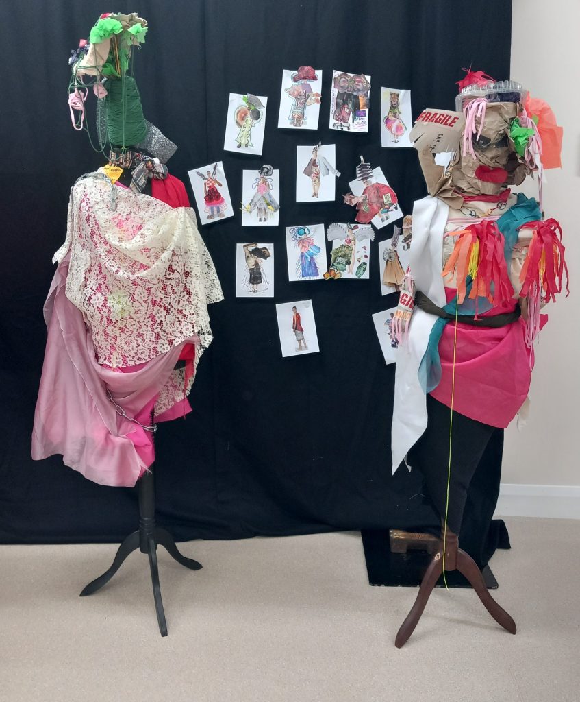 2 mannequins with fabric draped over them to give the appearance of dresses